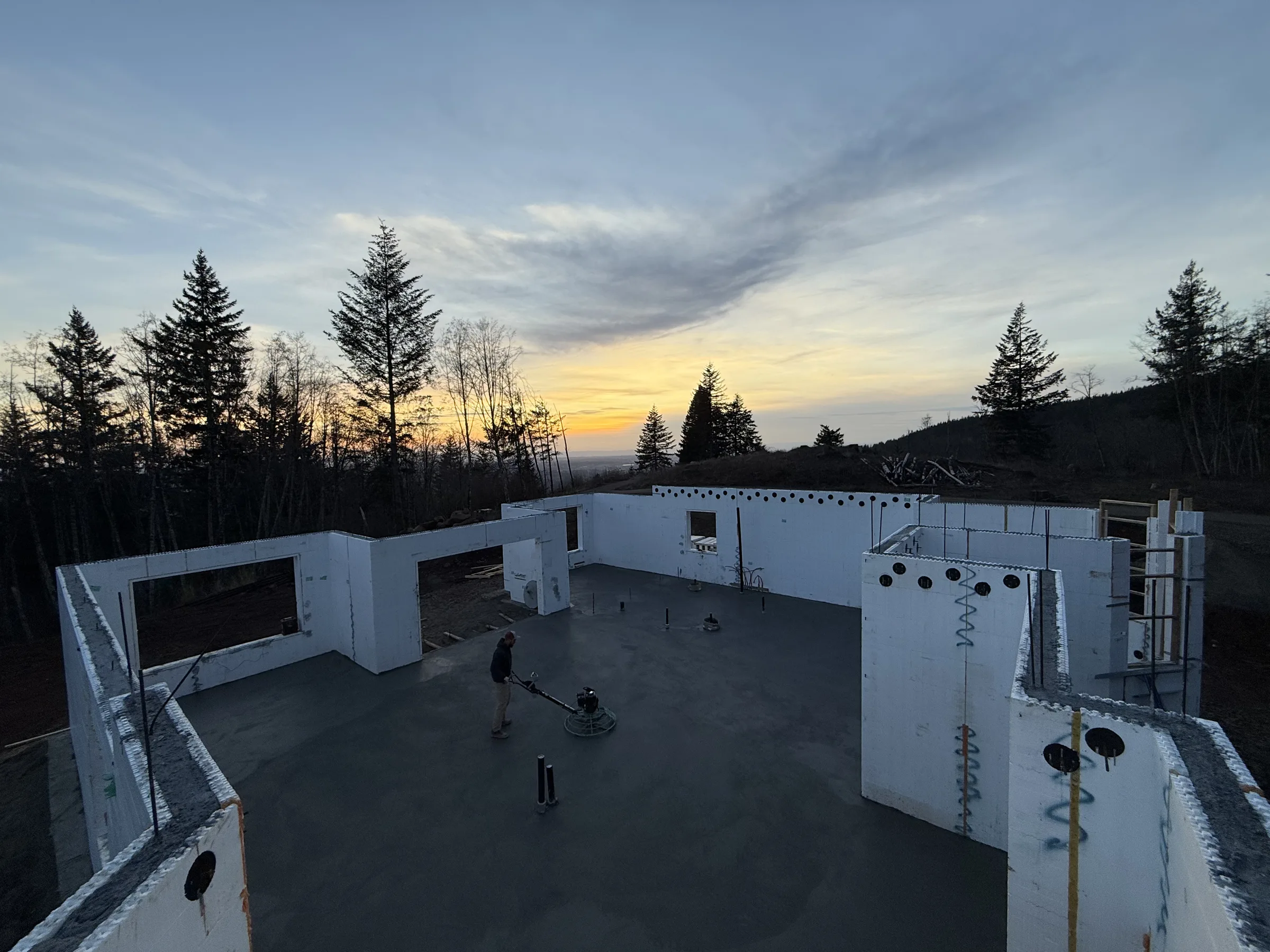 Power-troweling a fresh slab inside ICF walls at sunset
