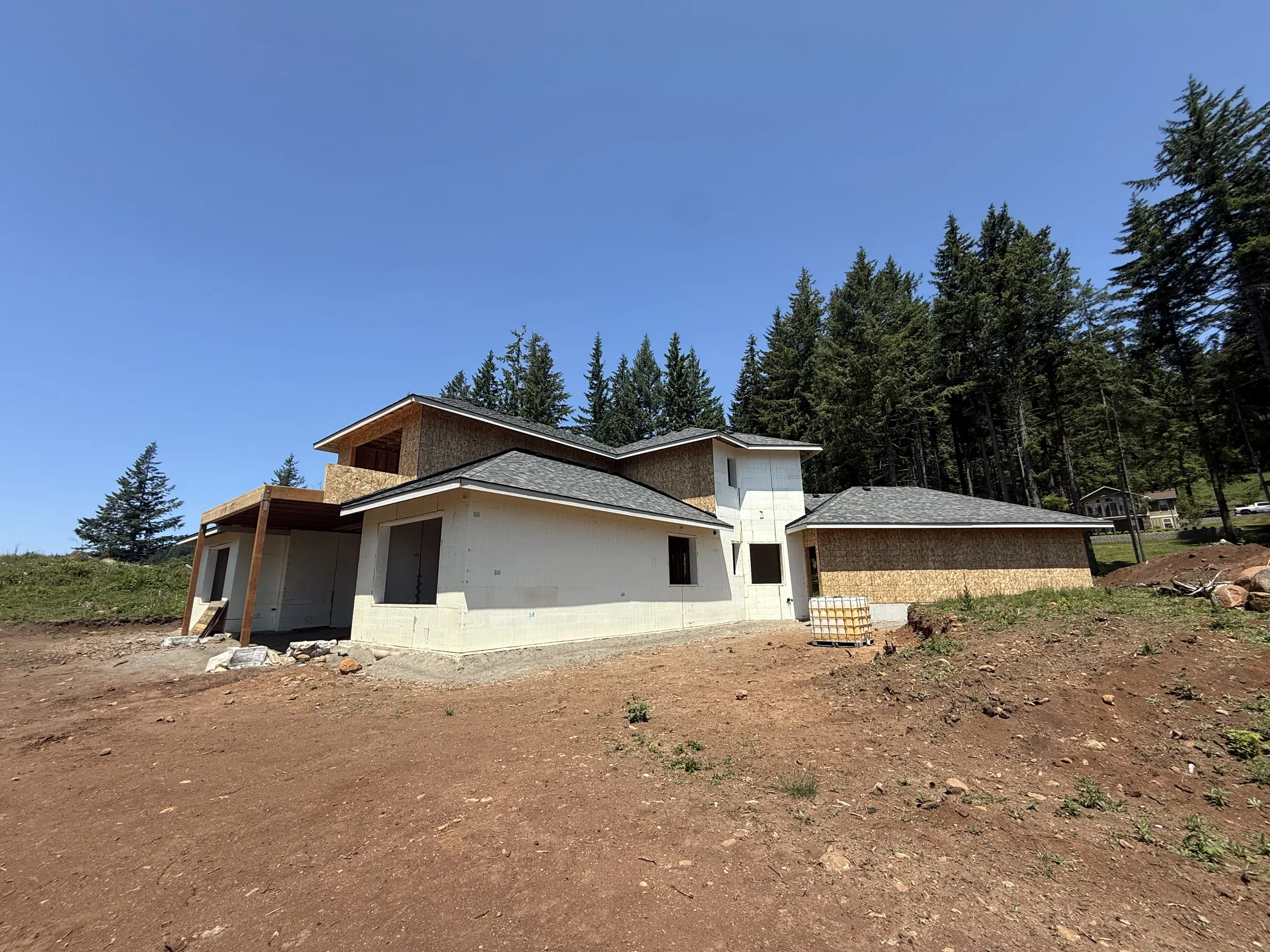 ICF home with sheathed gables and roof on, forest behind