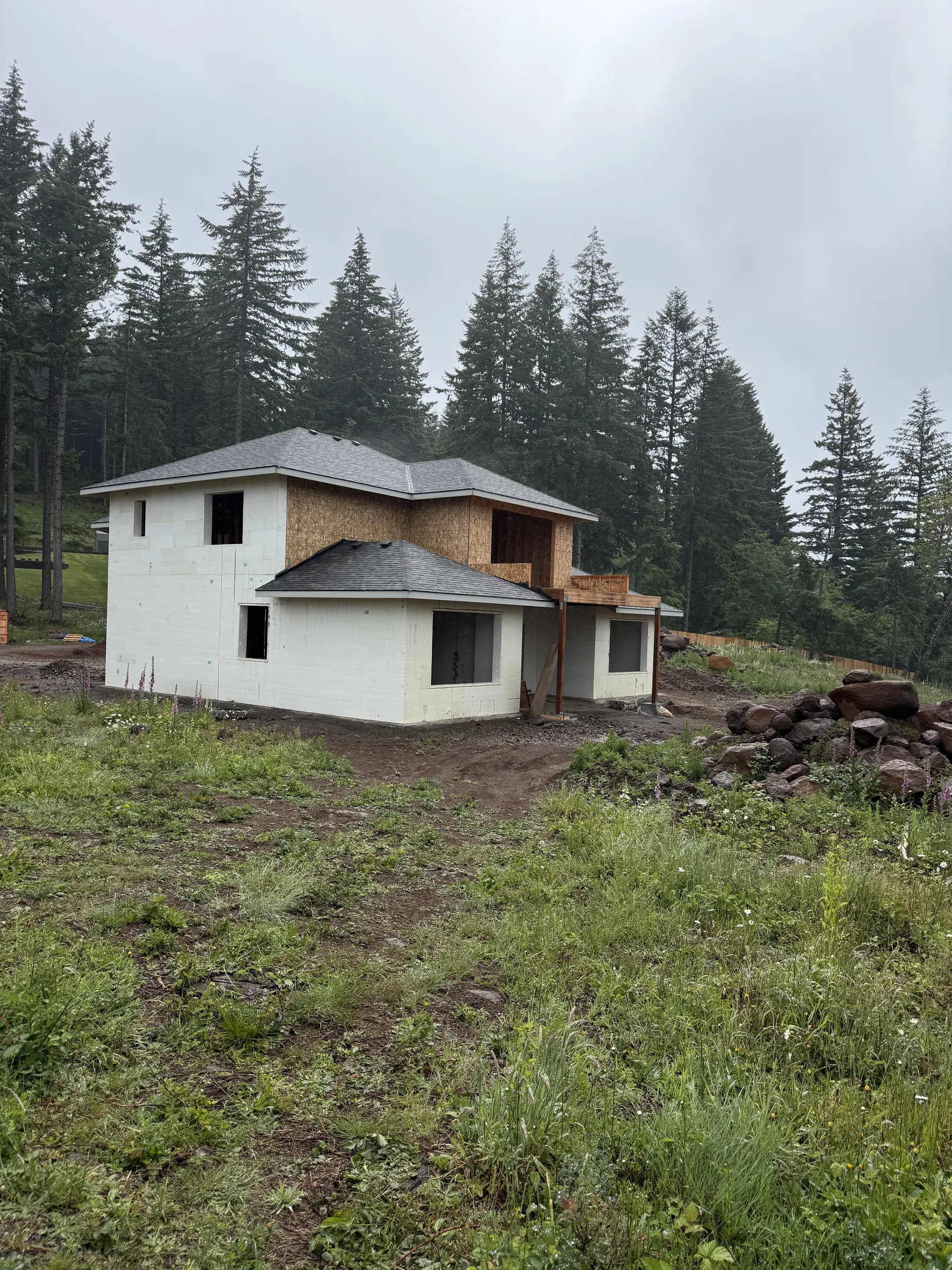 ICF home with grey shingled roof in low forest mist