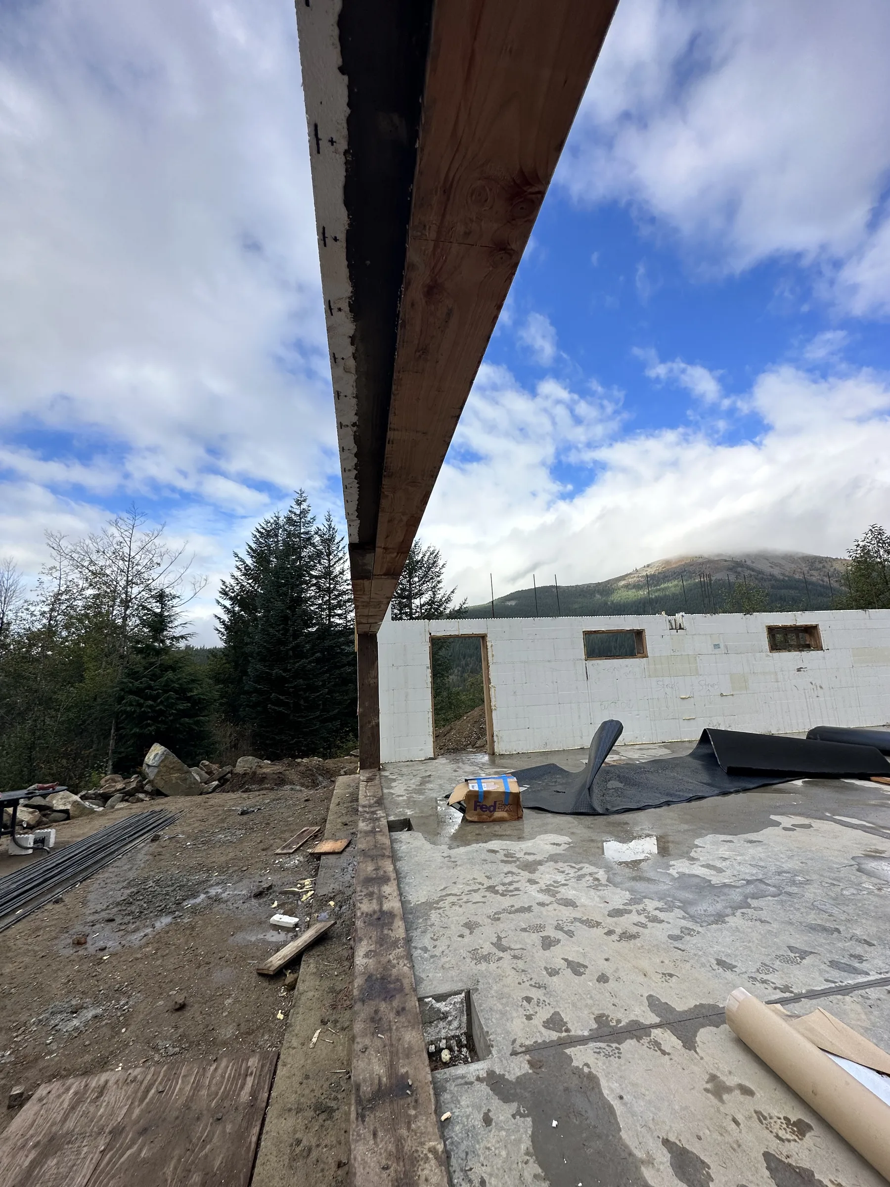 Sight line along a glulam beam over a curing slab toward the mountains